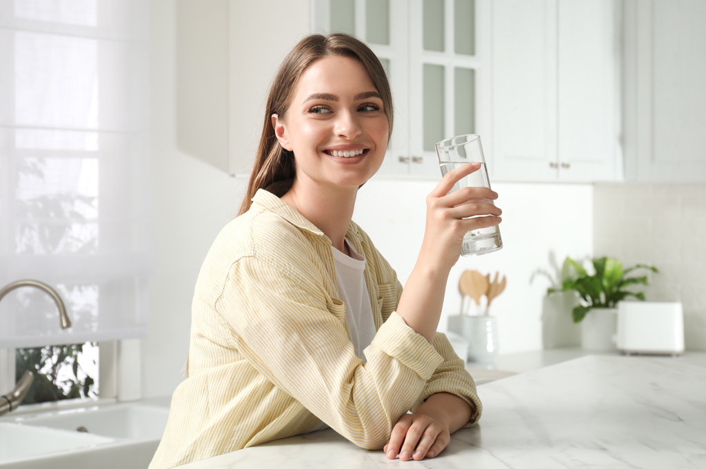 woman drinking glass of water at marble counter